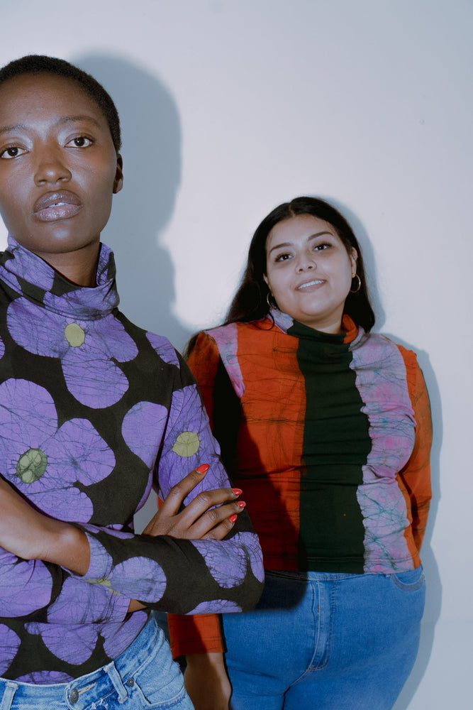 Two people in stylish, colorful clothing, faces obscured, showcasing the Stricta Turtleneck in Love Perfect print.