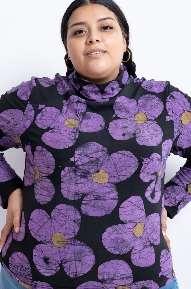 Person wearing the Stricta Turtleneck in Love Perfect print with its unique purple floral pattern.