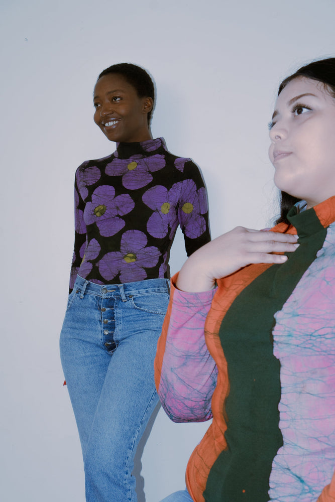 Two people in distinctively patterned outfits, featuring the Stricta Turtleneck in Love Perfect print.
