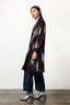 Side view of Theca Coat in handwoven indigo with red stripes, slim lapel, and silver boots, against a white background.