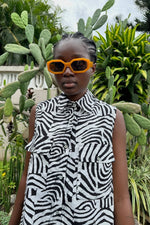 Comfortable Tropicana Dress with woodgrain-inspired Long Division design. Model stands in front of cacti with sunglasses on.