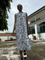 A woman walking in the black and white shirtdress wearing sunglasses, ready for any occasion.