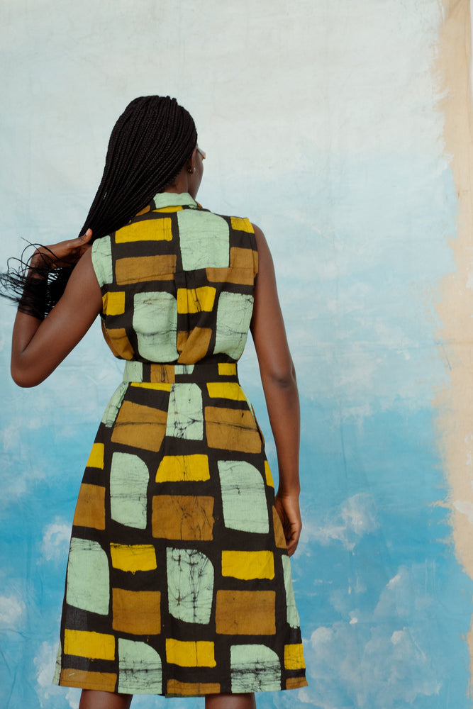 Back view of the dress in Pistacia, a hand batiked print features bold geometric shapes in earthy colors on black background.