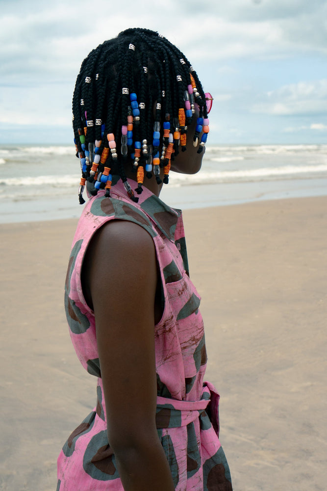 A woman with beads in her hair standing on the beach in a Sleeveless shirtdress with A-line skirt, with optional belt.