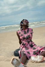 A woman relaxing on the beach in the Tropicana Dress, versatile for occasions or beachwear.